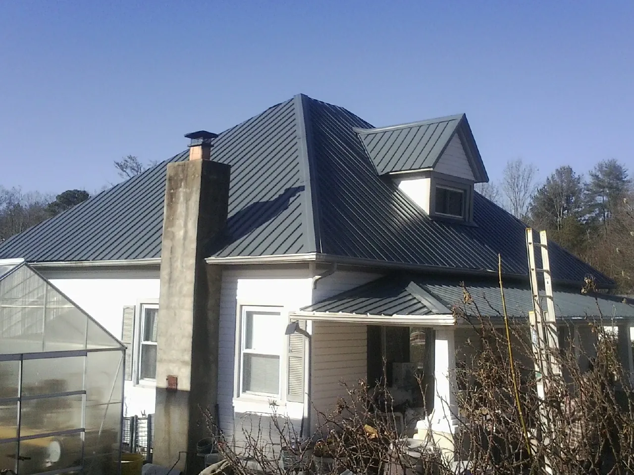 Dark blue standing seam metal roof on a white farmhouse with dormer — Slate & Tile Roof Repair by Roofing Brothers in Glasford