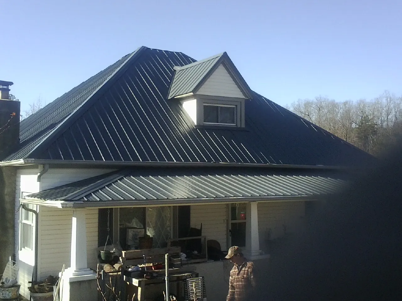 Dark blue standing seam metal roof with a dormer above a front porch in Glasford