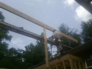 Carpenter setting a ridge beam over a new addition frame — Ice Dam Removal by Roofing Brothers in Glasford