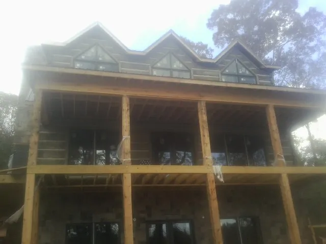 Dormers and porch framing on a large log home under construction — Roof Coating work by our crew in Glasford