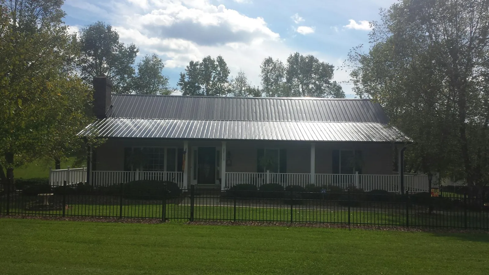Gray metal roof on a brick ranch with a full width front porch — Gutter Guard Installation work by our crew in Glasford