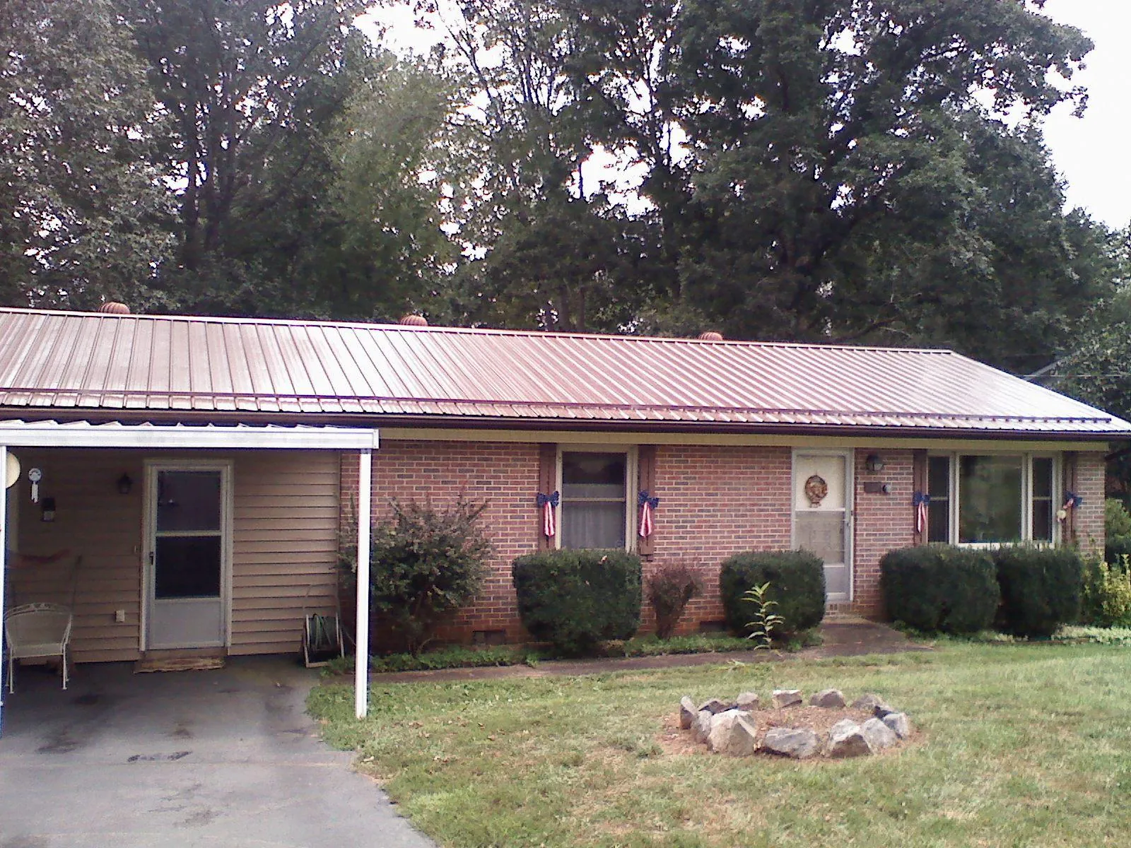 Bronze metal roof and carport on a brick ranch home — Roof Repair work by our crew in Glasford