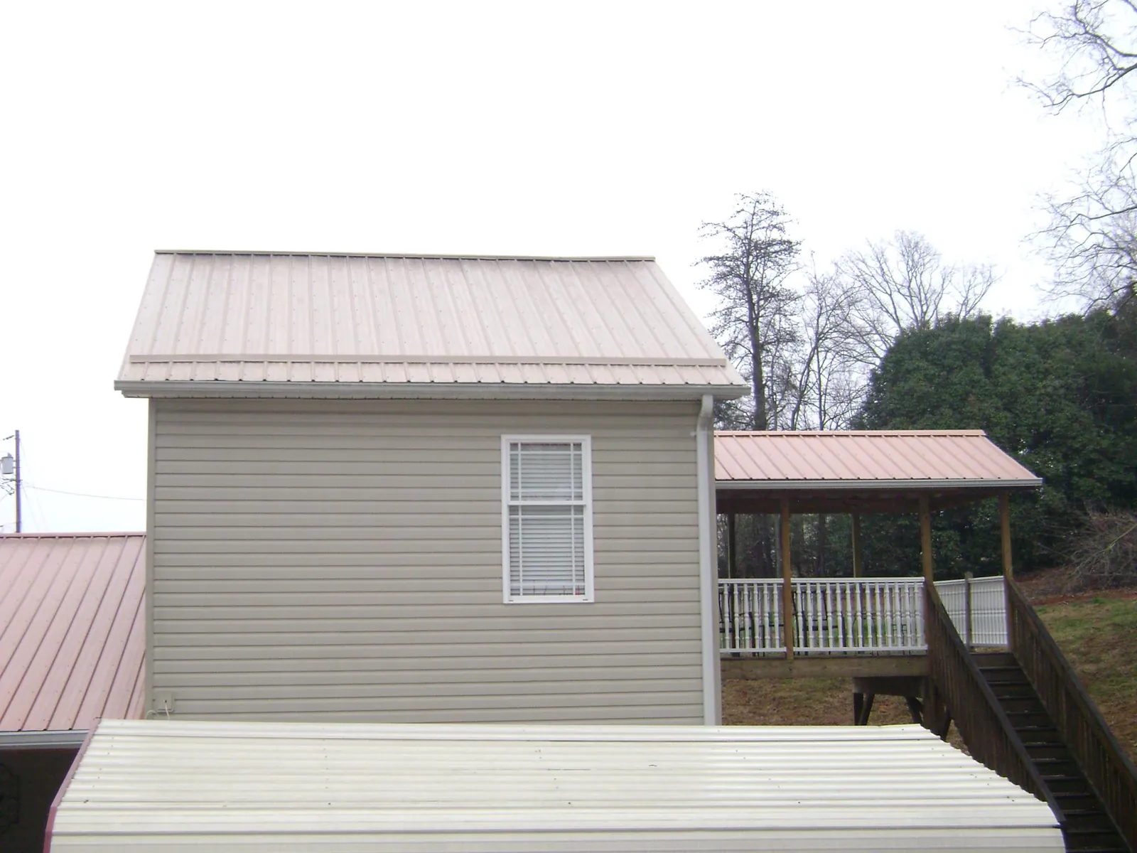 Tan metal roofs on a two story addition and attached porch, from a Roof Replacement job in Glasford