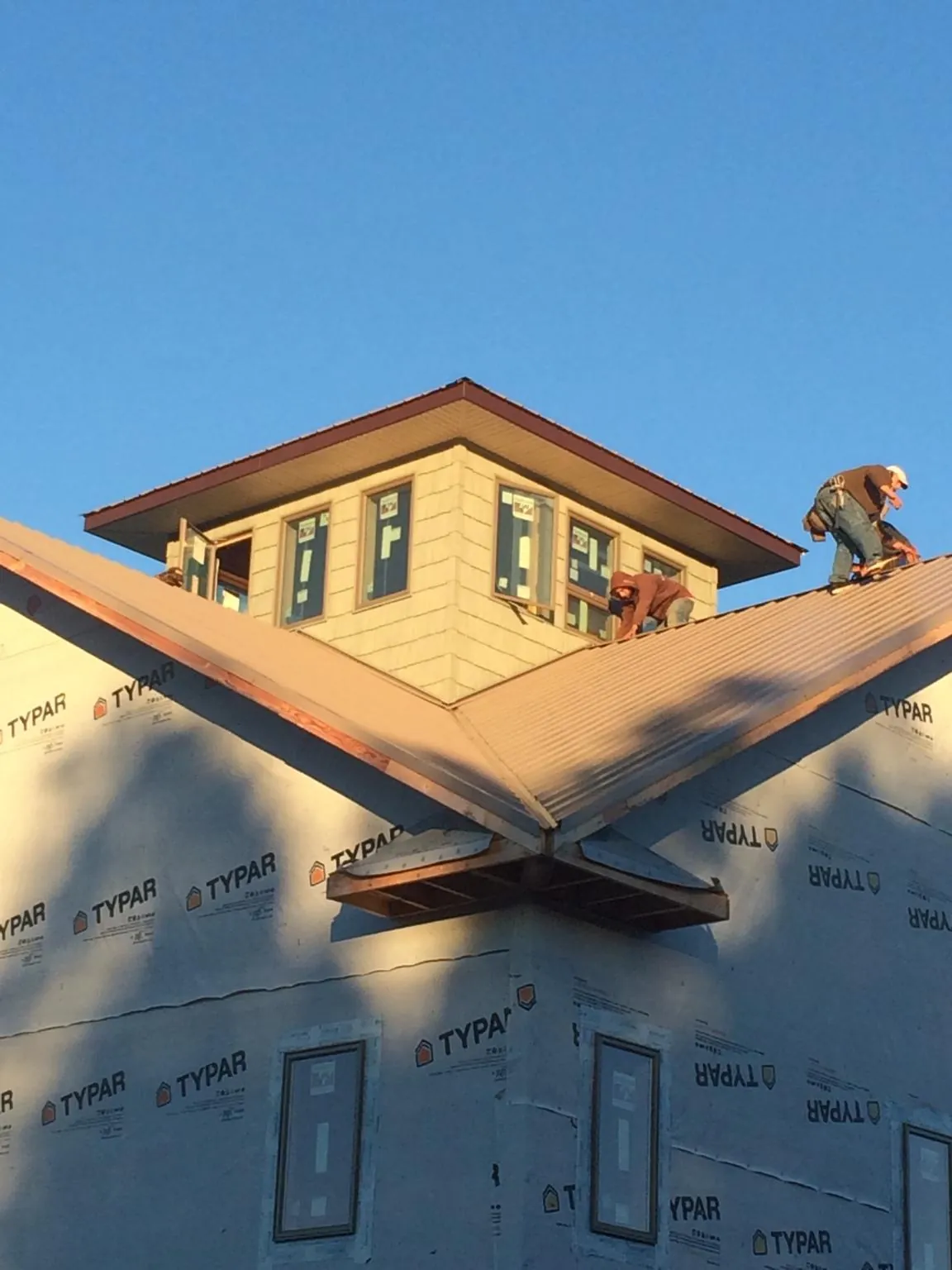 Roofers working around a rooftop cupola on a new metal roof at sunset — Roof Waterproofing in Glasford by Roofing Brothers